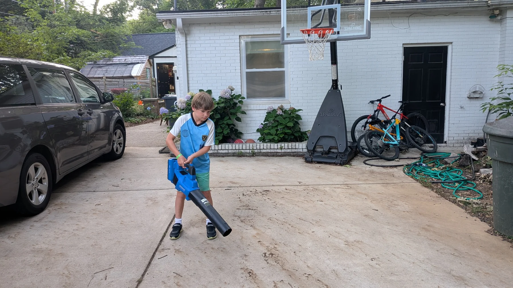 Brady using a leaf blower to clean a driveway